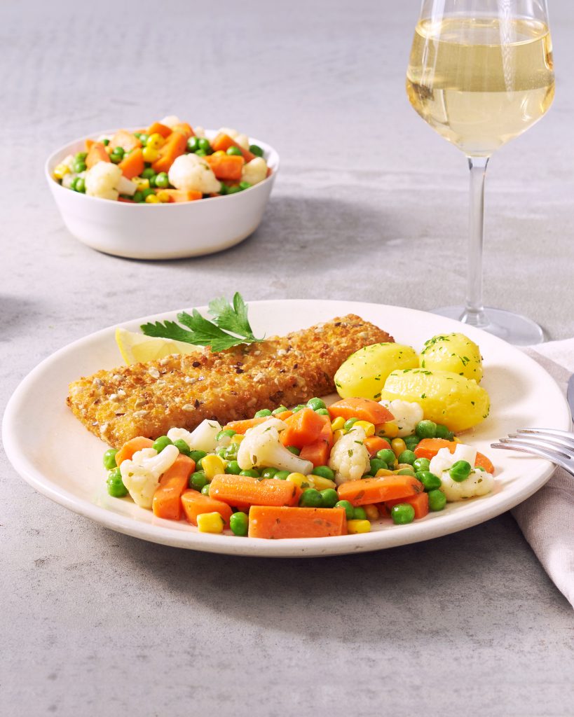 Ein Teller mit FRoSTA paniertem Fischfilet, Salzkartoffeln und FRoSTA Buttergemüse mit Erbsen, Karotten, Mais und Blumenkohl.